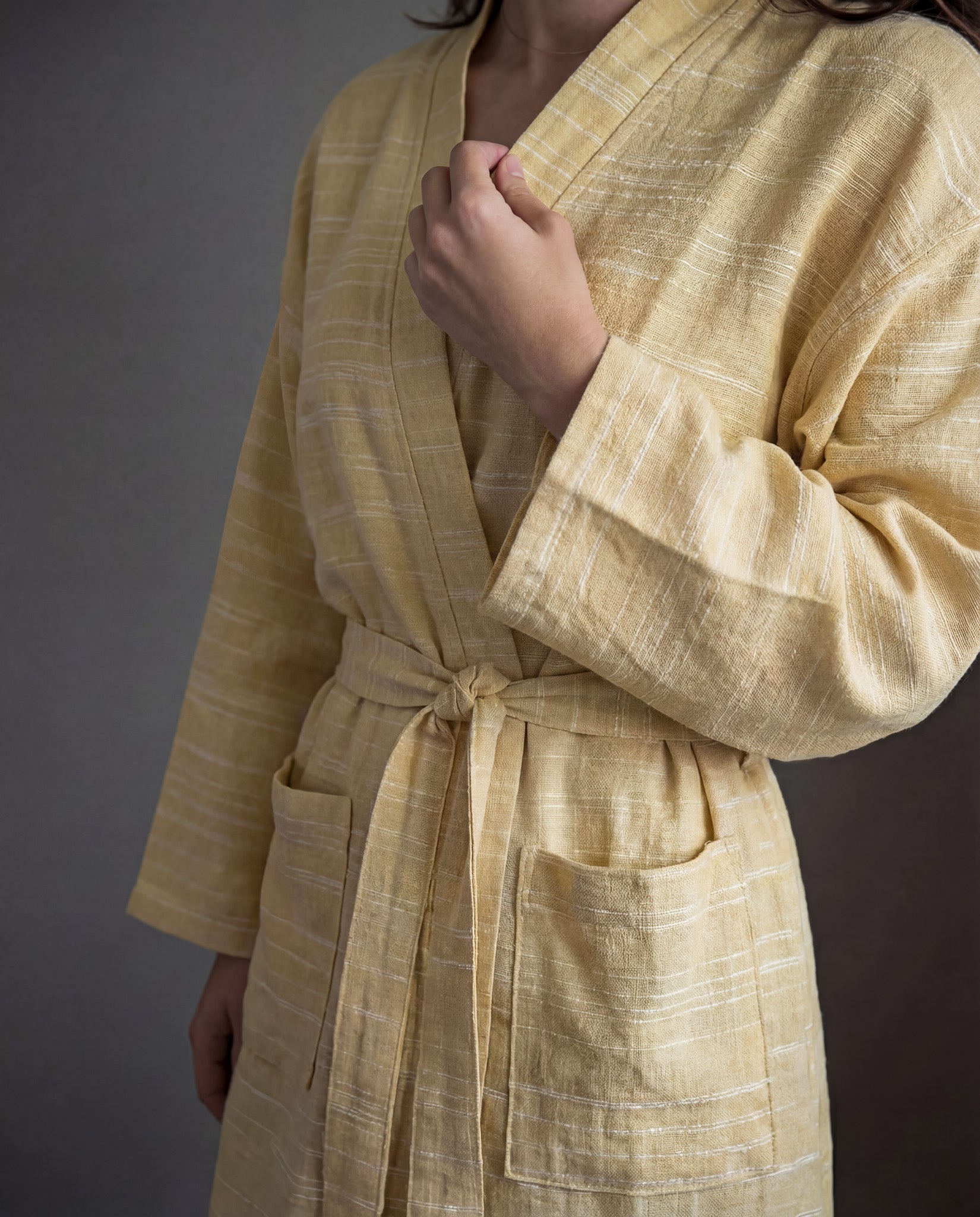 Person wearing a yellow robe against a gray background