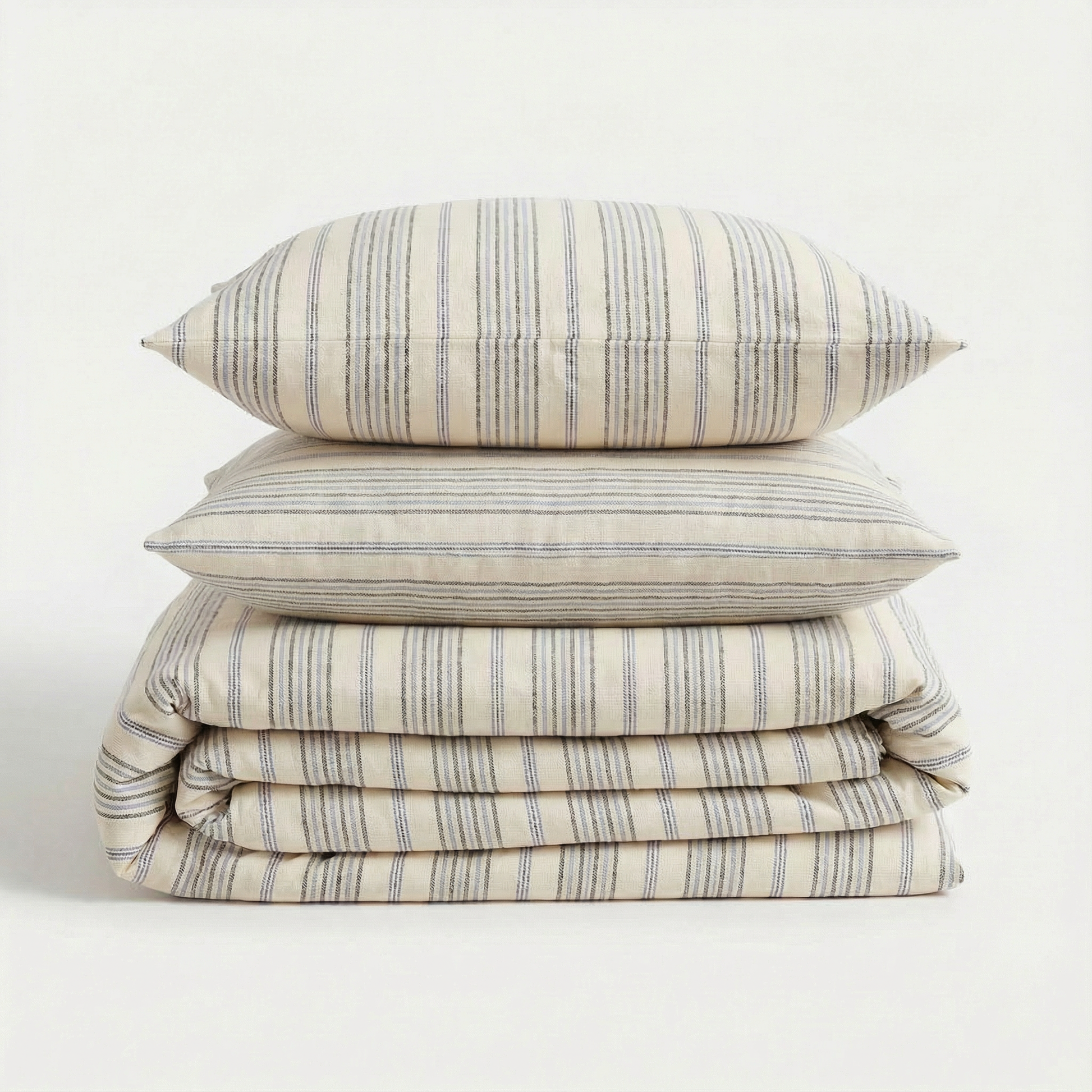 Stack of blue striped bedding set with a pillow on a white background