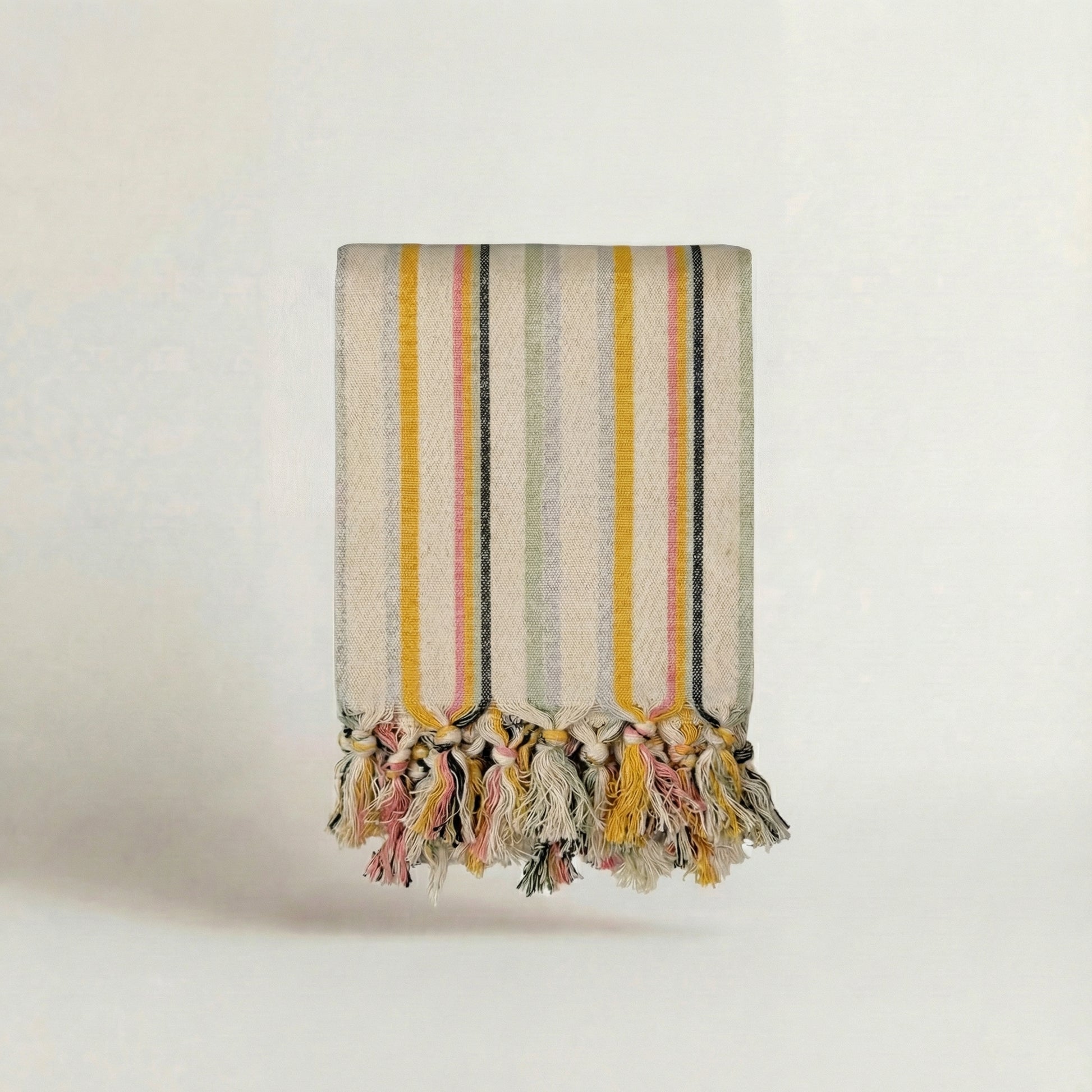 Handwoven towel with pastel pink, yellow, green, blue stripes and tassels on a light background