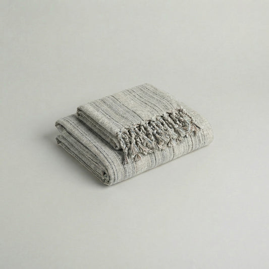 Folded slub cotton handwoven towel set with tassels on a light gray background