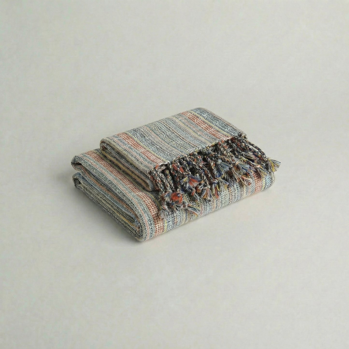 Folded handwoven slub turkish cotton towel with colorful patterns on a light gray background from atelier orea