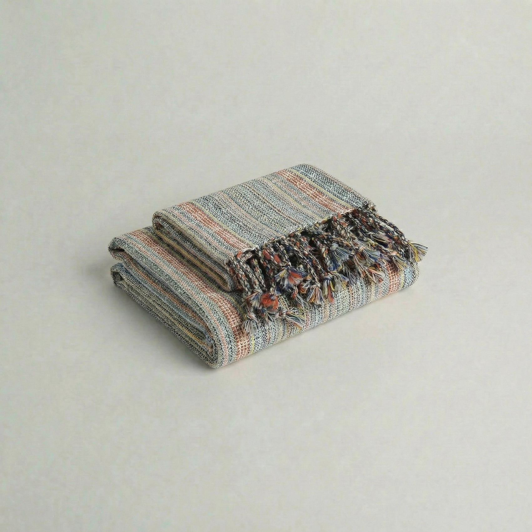 Folded handwoven slub turkish cotton towel with colorful patterns on a light gray background from atelier orea