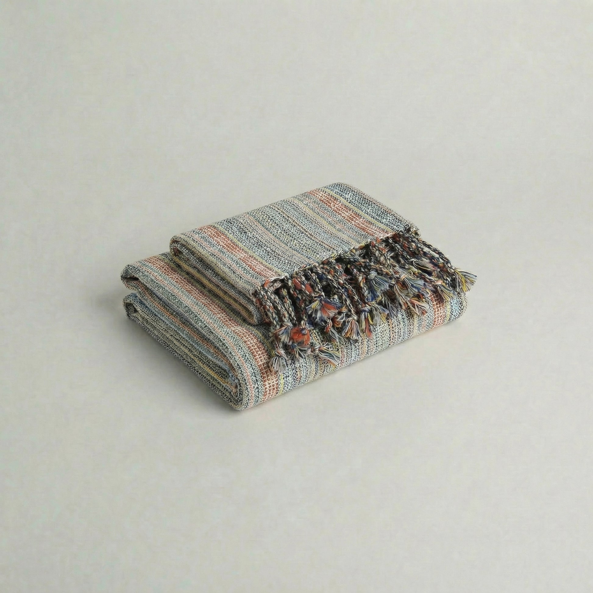 Folded handwoven slub turkish cotton towel with colorful patterns on a light gray background from atelier orea