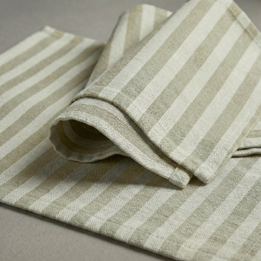 Folded ecru and beige striped cotton placemat and napkin on a gray surface