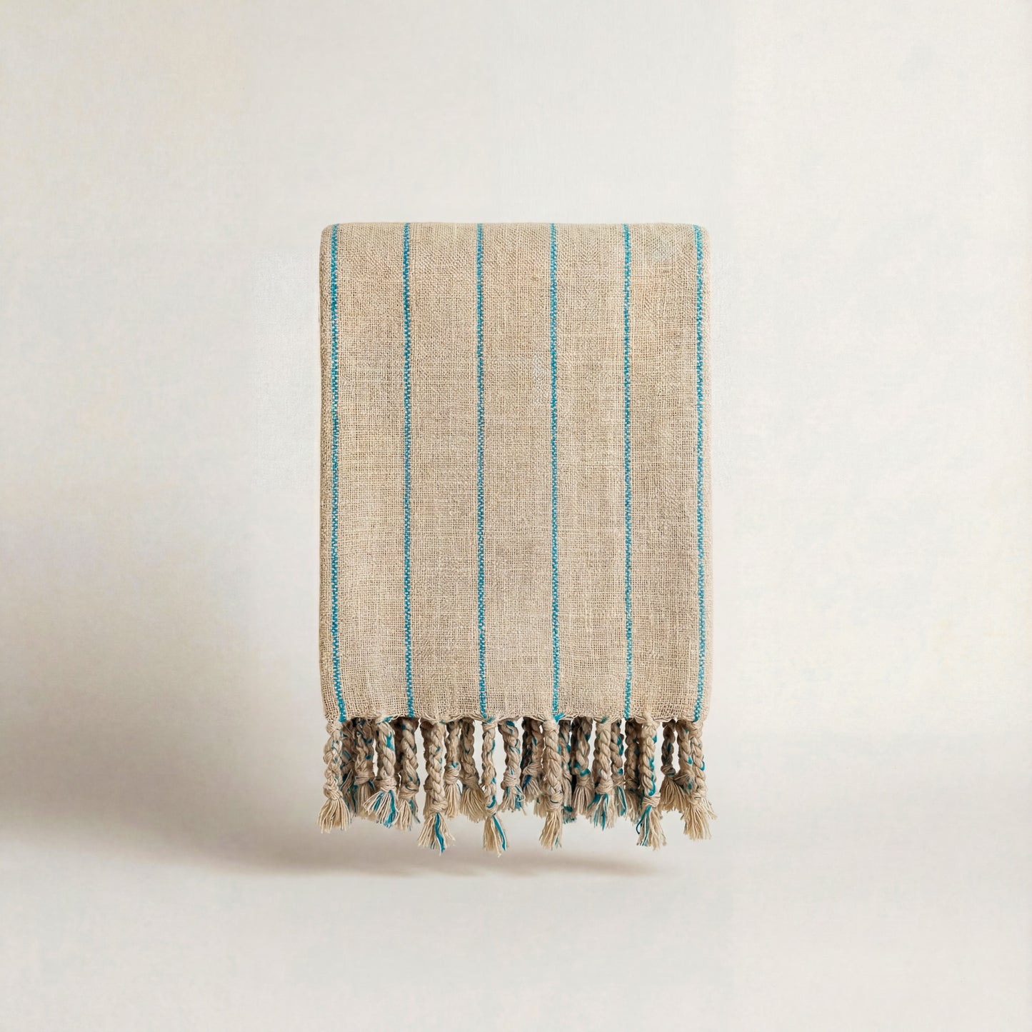 Bright blue Striped handwoven atelier orea towel with tassels on a light background