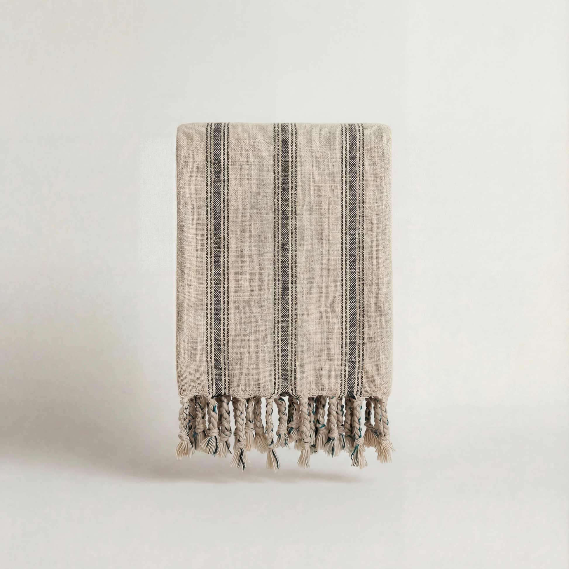 Textured handwoven atelier orea towel with striped pattern and tassels on a light background