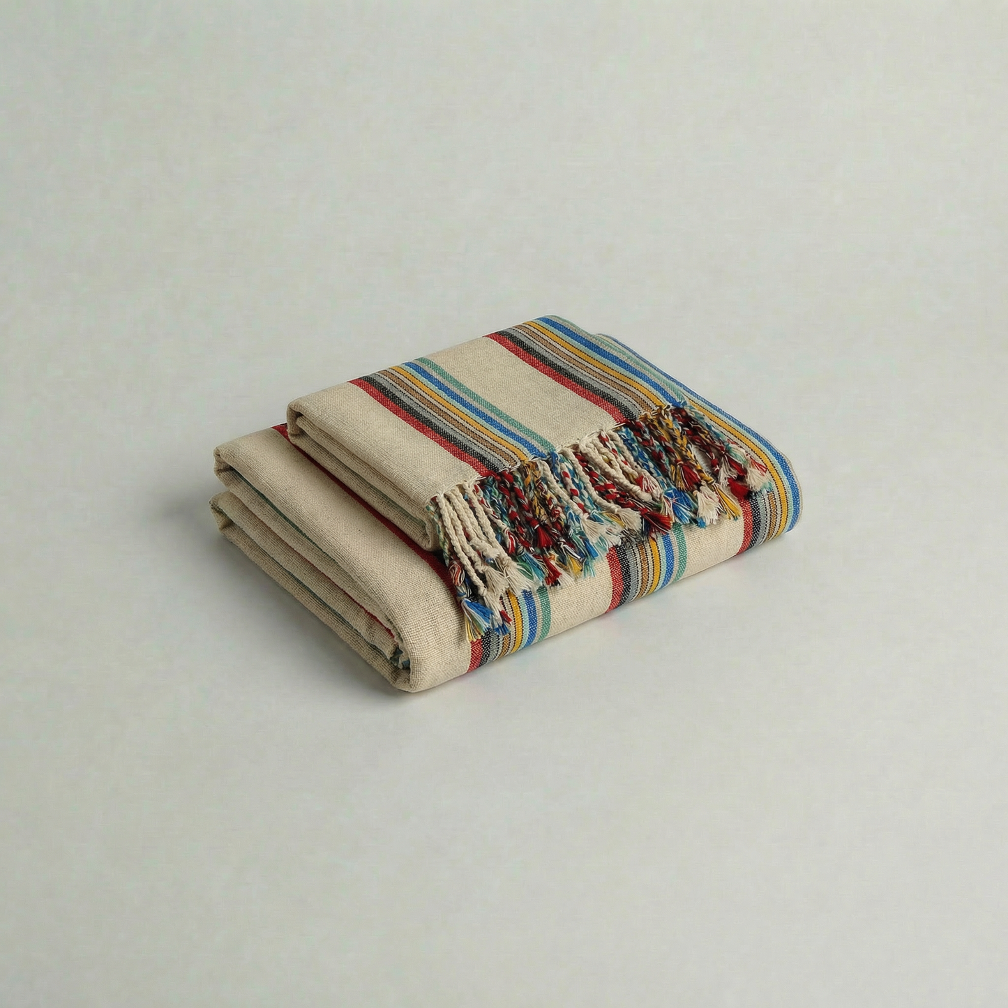 Folded hadnwoven atelier orea turkish cotton towel with colorful stripes on a light gray background