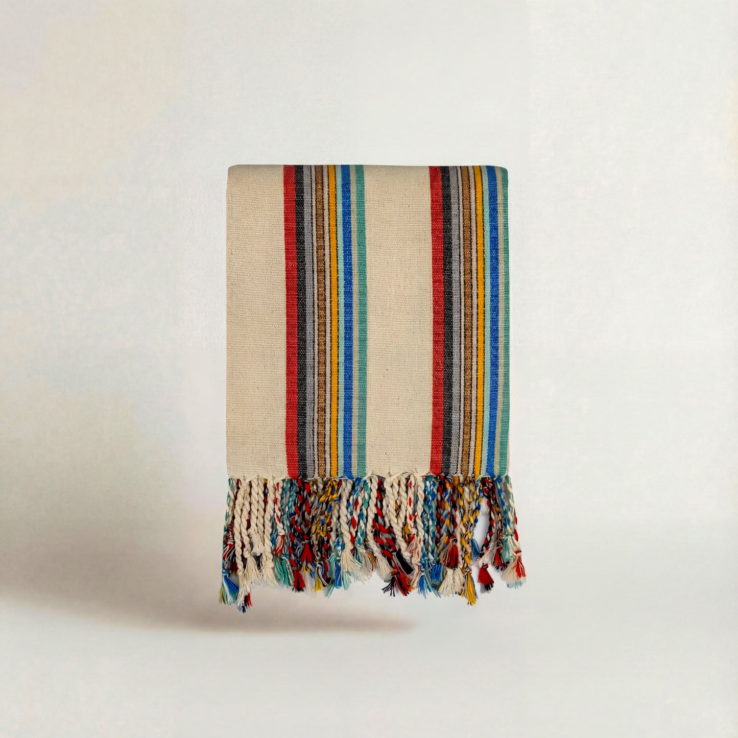 Multicolored striped handwoven atelier orea towel with tassels on a light background