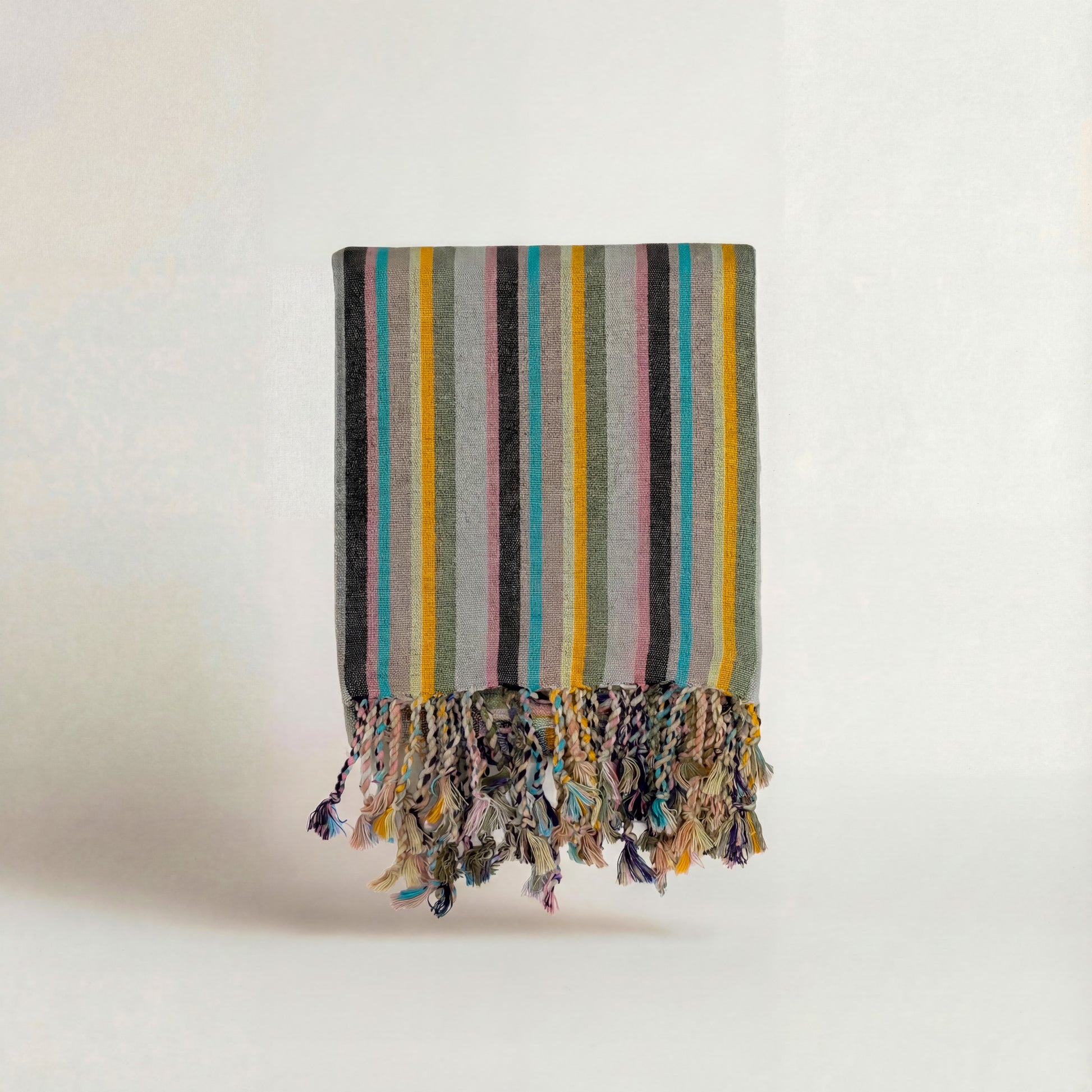 Multicolored striped handwoven atelier orea towel with tassels on a white background