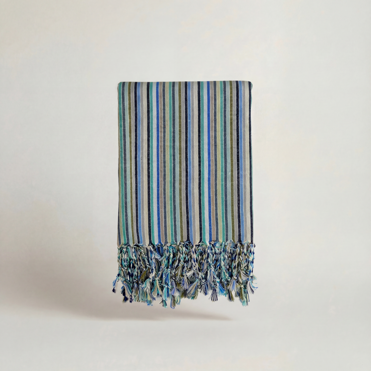 Striped handwoven atelier orea towel with tassels on a light background