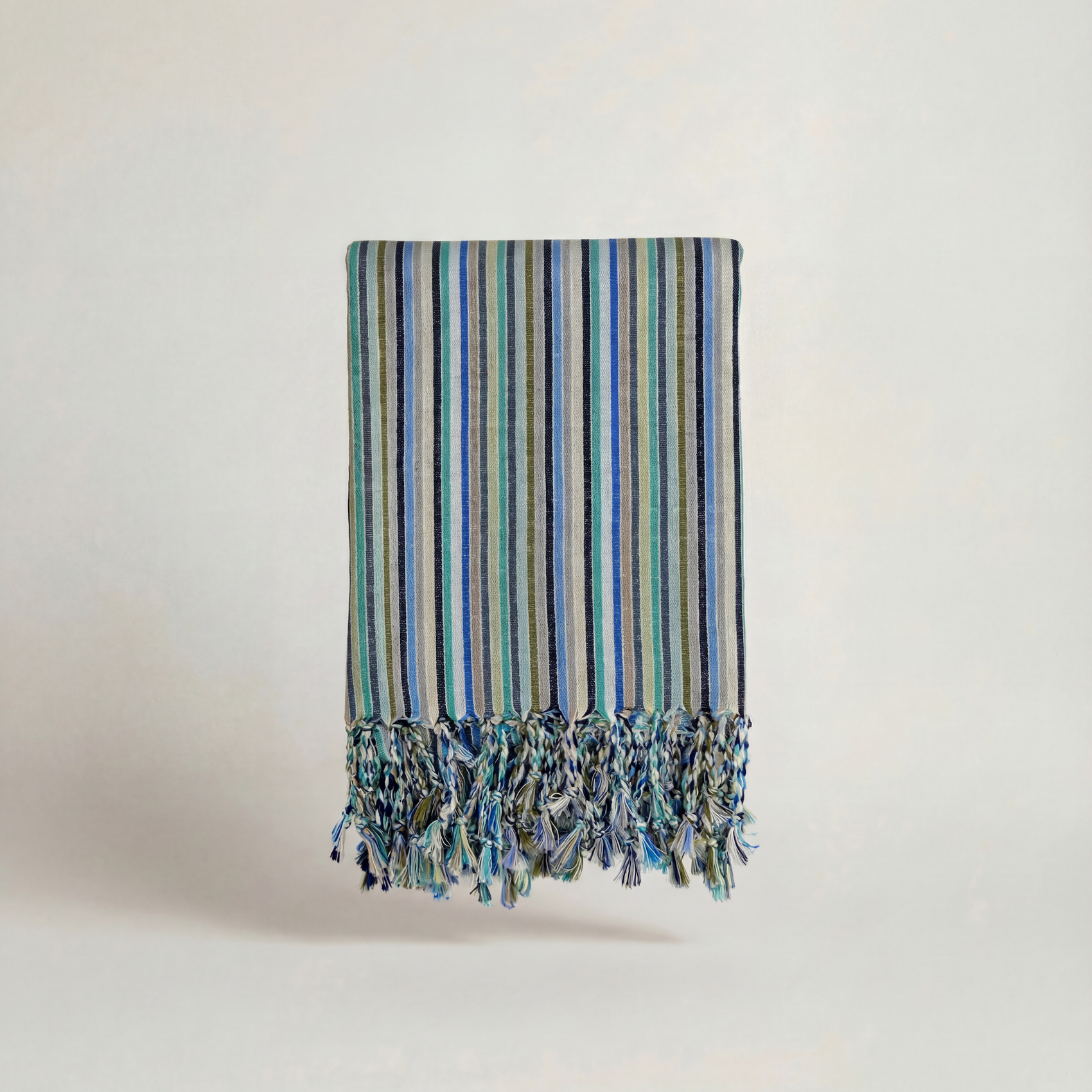 Striped handwoven atelier orea towel with tassels on a light background