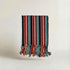 Striped handwoven atelier orea towel in red turquoise navy with tassels on a light background
