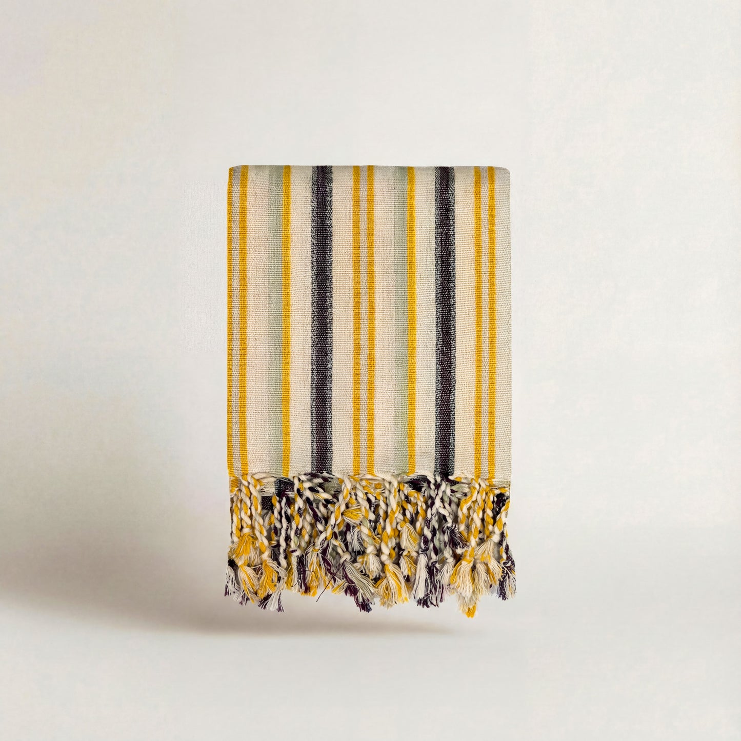 striped handwoven atelier orea towel with yellow, black, and white pattern on a light background