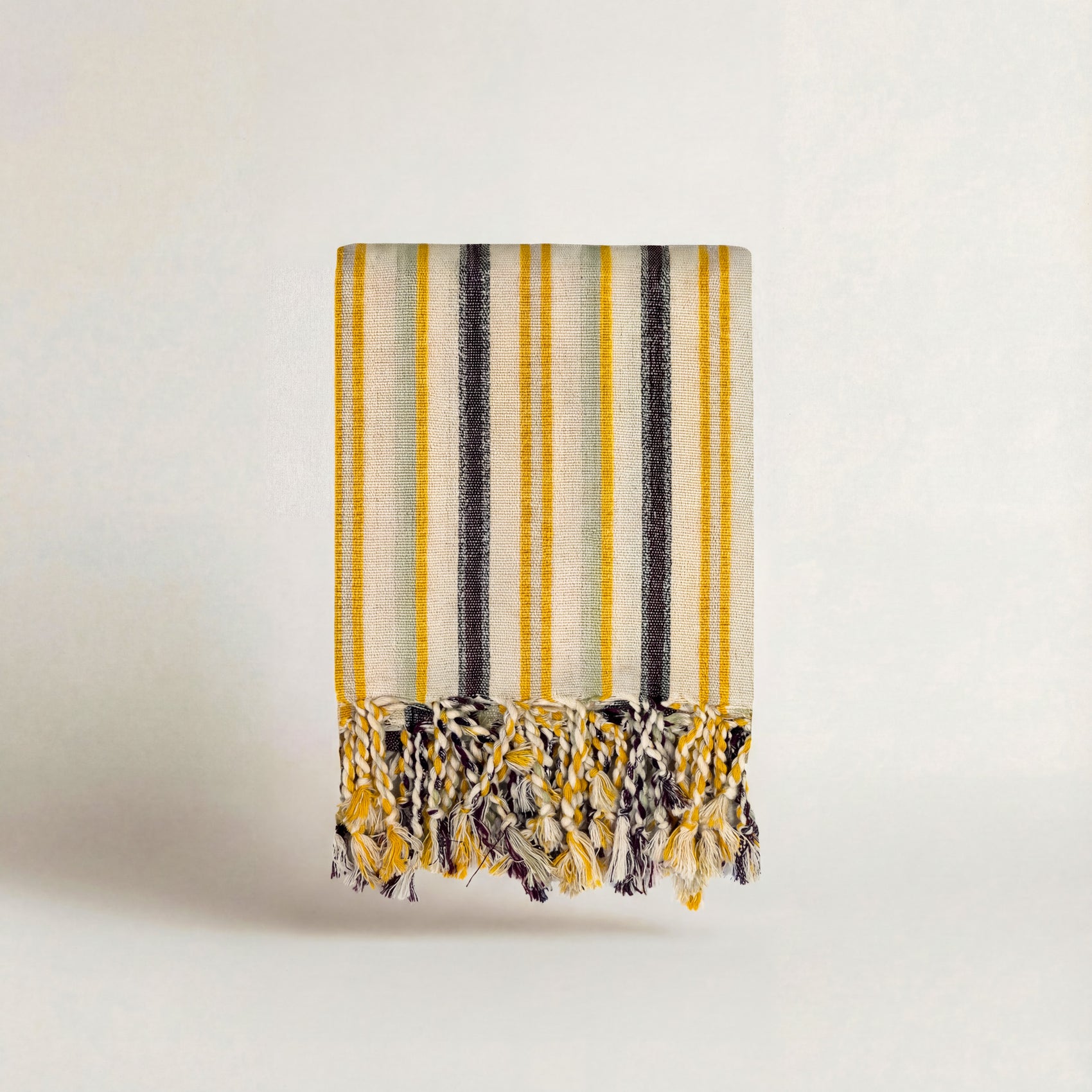 striped handwoven atelier orea towel with yellow, black, and white pattern on a light background